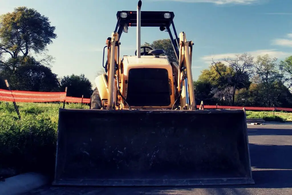 Bulldozer parked on the concrete parking lot at a construction site. Post on the topic of are bulldozers street legal.