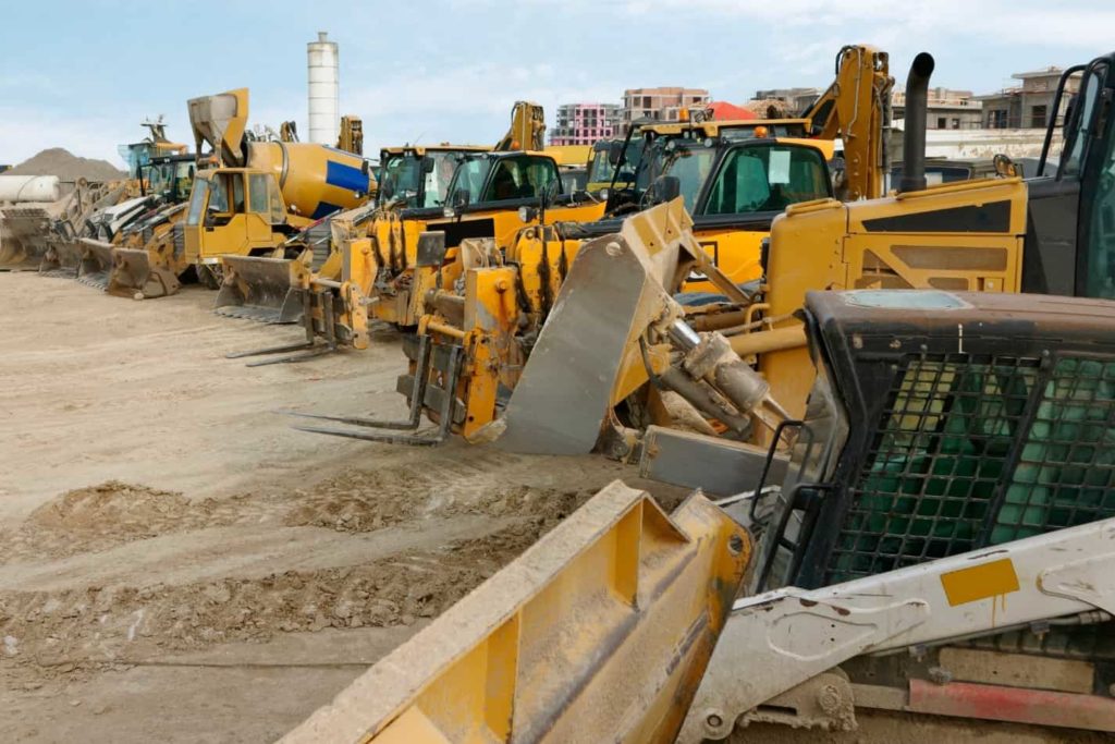 loads of different types of heavy machinery on a flat sandy ground from bulldozers to cement pourer and more