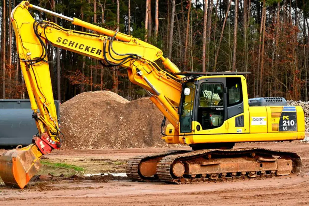 backhoe on a dirt lot digging up dirrt to pile