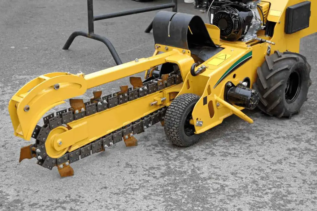 Heavy duty trenching machine, yellow in color with a thick digging blade