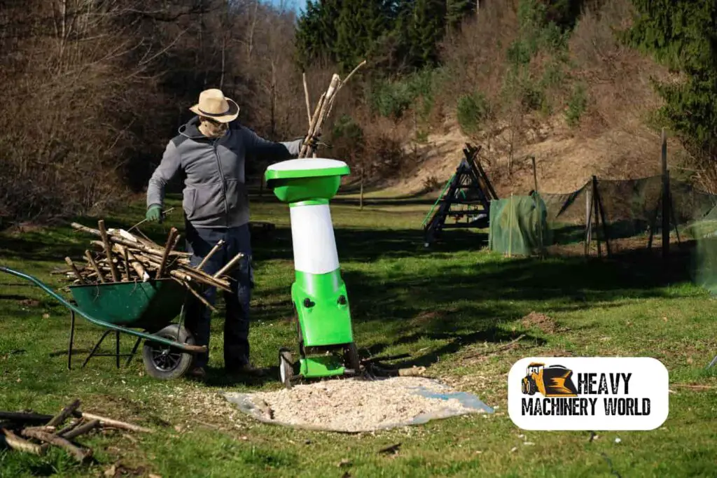 Man using a small tree shredder in his backyard