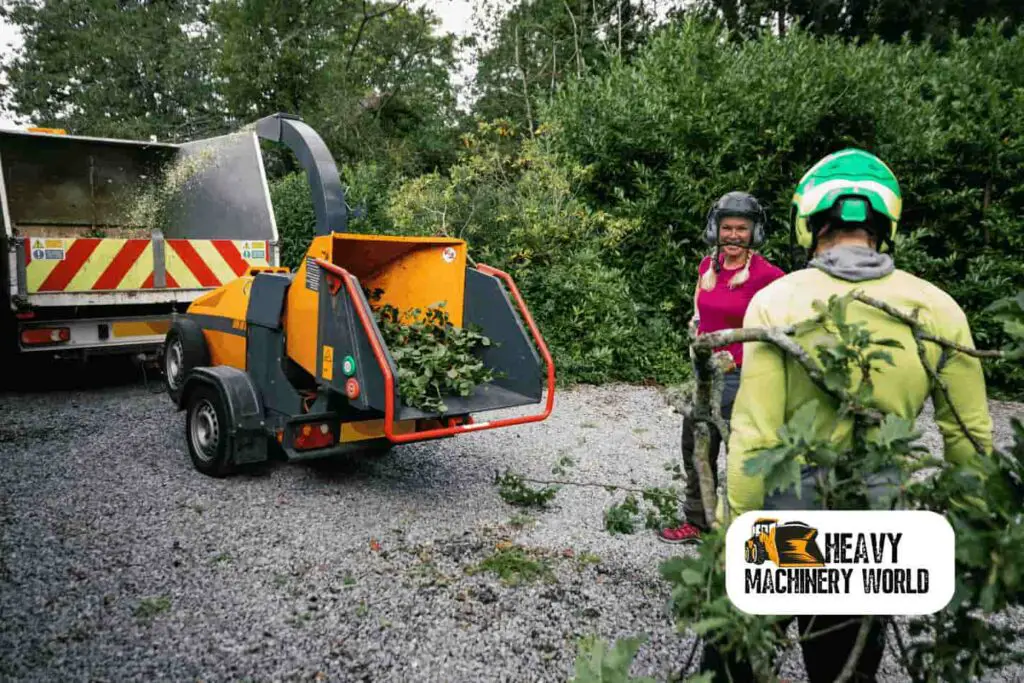 two people using a tree shredder to remove branches and turn into chips